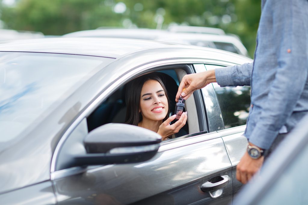 Buying used car. Car Dealer Inventory. Used cars store. Male wants to buy the car. Close-up of hand with a wrist watch, holding key from auto, finance for car concept. Happy life. Blurred background.